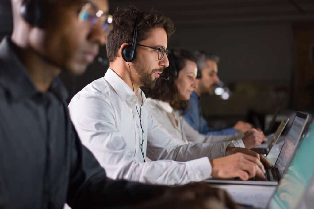 IT technicians working on laptops with headsets, symbolizing round-the-clock availability and expertise in 24/7 IT support for businesses.